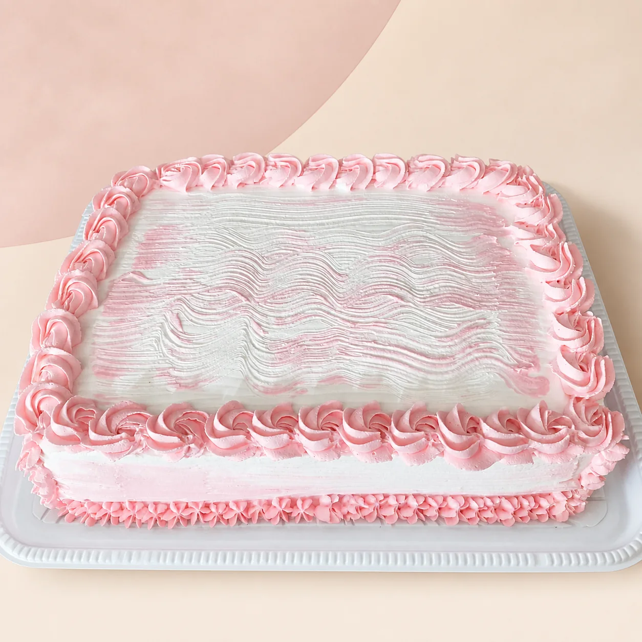 Bolo retangular branco e rosa com acabamento ondulado